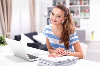 Elinde evrakları olan kadın masanın üstünde oturuyor.