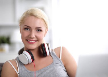Evdeki genç ve güzel kadın kanepede oturup müzik dinliyor.