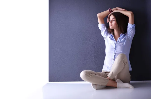 Young woman sitting on the floor near dark wall — Stock Photo, Image