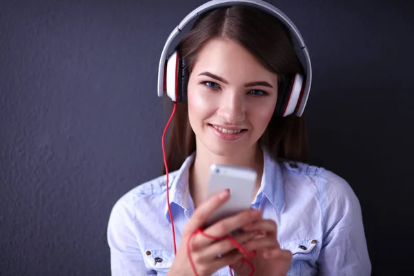Χαμογελαστό κορίτσι με ακουστικά που κάθεται στο πάτωμα κοντά σε τοίχο — Φωτογραφία Αρχείου