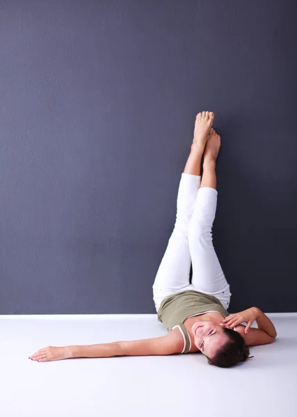 Молодая женщина лежит на полу с поднятыми ногами — стоковое фото