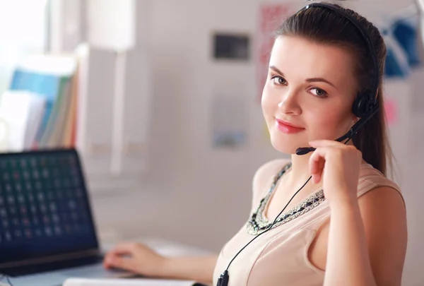 Vacker affärskvinna som arbetar vid sitt skrivbord med headset och laptop — Stockfoto