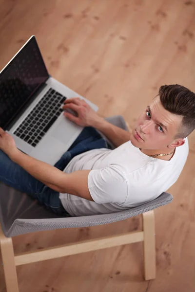 Young man sitting on chair with laptop — Stock Photo, Image