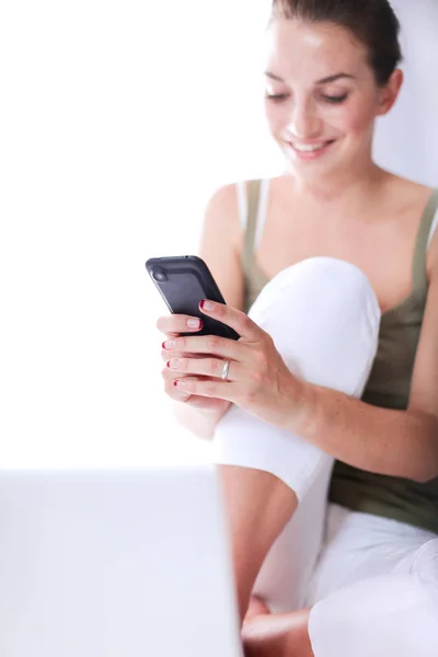 Aantrekkelijke Kaukasische meisje zittend op de vloer met telefoon — Stockfoto