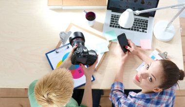 Dizüstü bilgisayar ile masaya oturan iki kadın fotoğrafçı