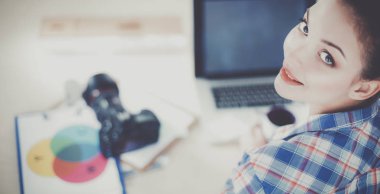 Masada dizüstü bilgisayarla oturan kadın fotoğrafçı.