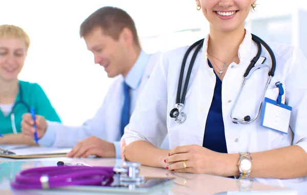 Bella giovane sorridente medico femminile seduto alla scrivania — Foto Stock