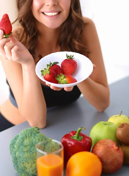 Menina sentada na cozinha na mesa com frutas — Fotografia de Stock