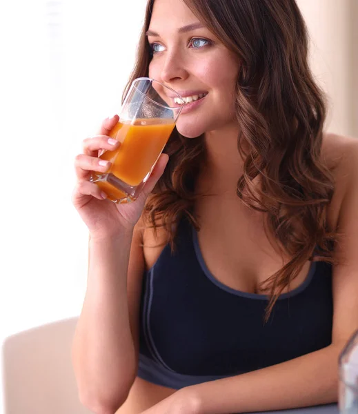 Fille assise dans la cuisine sur le bureau avec des fruits et des verres avec du jus — Photo