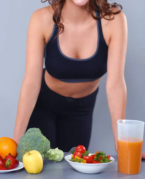 Mujer joven y hermosa de pie cerca del escritorio con verduras —  Fotos de Stock