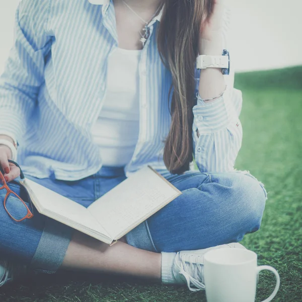 Young woman sitting with book on grass — Stock Photo, Image