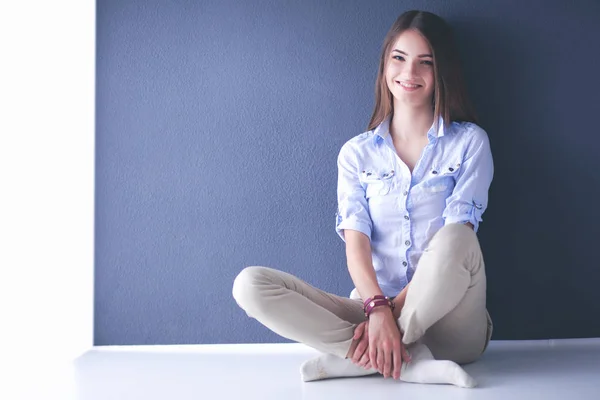 Young woman sitting on the floor near dark wall — Stock Photo, Image