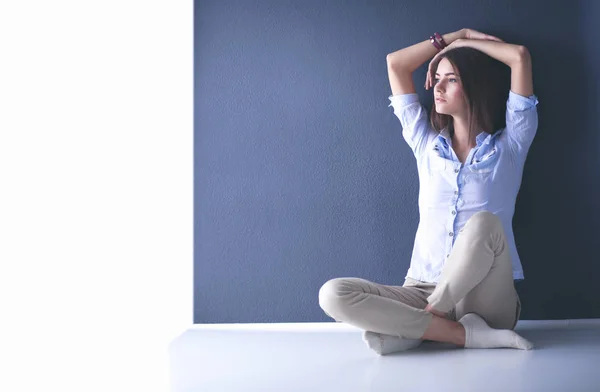 Mujer joven sentada en el suelo cerca de la pared oscura —  Fotos de Stock