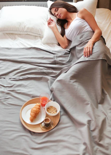 bir bardak süt ile yatakta oturan genç kadın