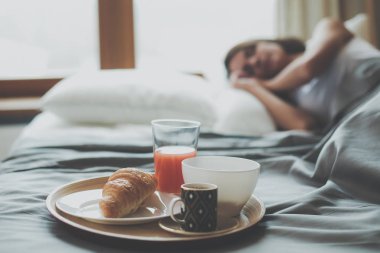 bir bardak süt ile yatakta oturan genç kadın