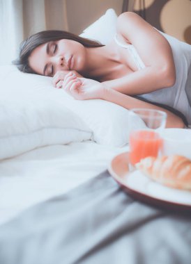 bir bardak süt ile yatakta oturan genç kadın