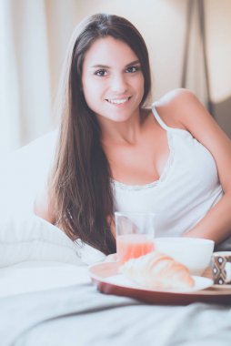 bir bardak süt ile yatakta oturan genç kadın