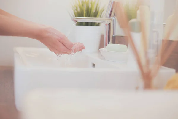 Jonge vrouw wassen haar gezicht met schoon water in badkamer — Stockfoto