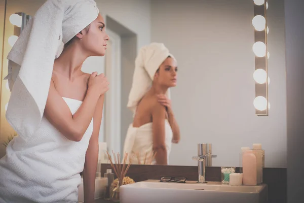 Młoda atrakcyjna kobieta stojąc przed lustrem w łazience — Zdjęcie stockowe