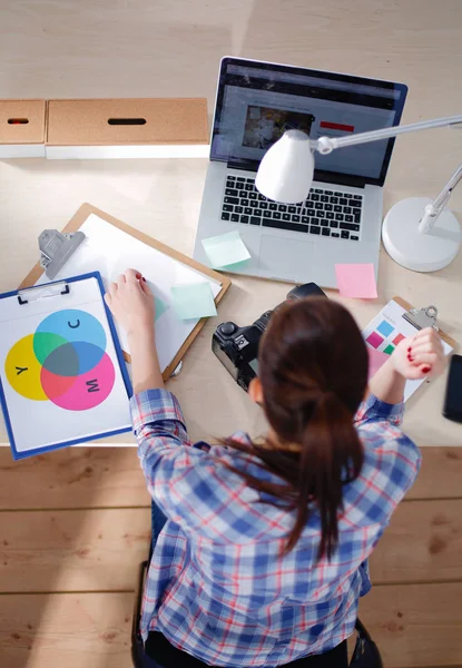 Vrouwelijke fotograaf zittend op het bureau met laptop — Stockfoto