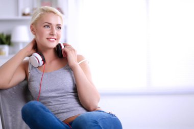 Evdeki genç ve güzel kadın kanepede oturup müzik dinliyor.
