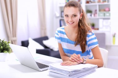 Elinde evrakları olan kadın masanın üstünde oturuyor.