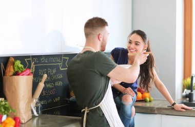 Bir çift evdeki mutfaklarında birlikte yemek pişiriyor.