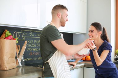 Bir çift evdeki mutfaklarında birlikte yemek pişiriyor.