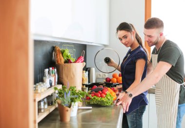 Bir çift evdeki mutfaklarında birlikte yemek pişiriyor.