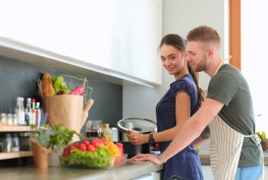 Bir çift evdeki mutfaklarında birlikte yemek pişiriyor.