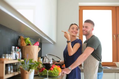 Bir çift evdeki mutfaklarında birlikte yemek pişiriyor.