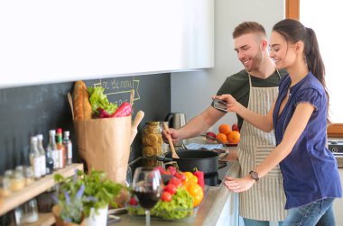 Bir çift evdeki mutfaklarında birlikte yemek pişiriyor.