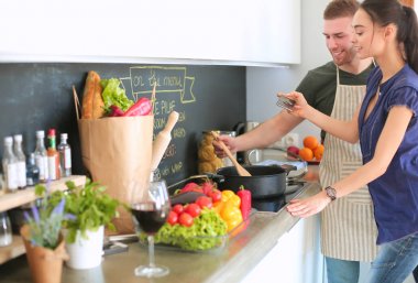 Bir çift evdeki mutfaklarında birlikte yemek pişiriyor.