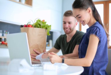 Çift evde mutfak içinde laptop ile onların fatura ödeme