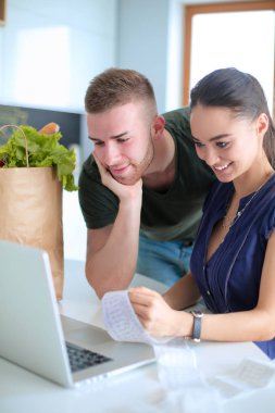 Çift evde mutfak içinde laptop ile onların fatura ödeme