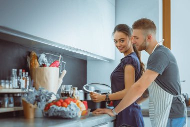 Bir çift evdeki mutfaklarında birlikte yemek pişiriyor.
