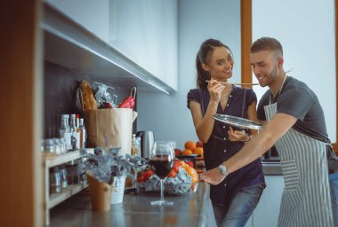 Bir çift evdeki mutfaklarında birlikte yemek pişiriyor.