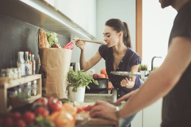 Bir çift evdeki mutfaklarında birlikte yemek pişiriyor.