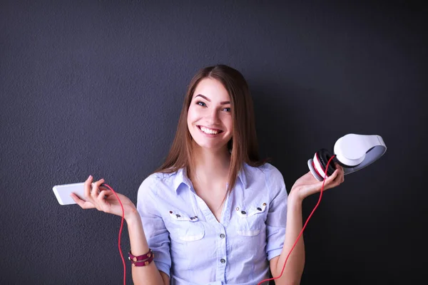 Chica sonriente con auriculares sentados en el suelo cerca de la pared — Foto de Stock