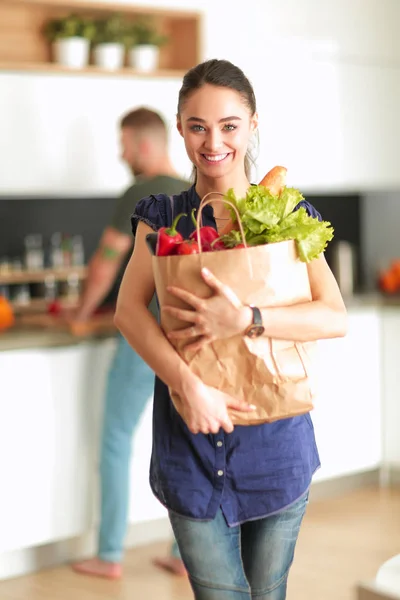 Jong stel in de keuken, vrouw met een zak boodschappen doen — Stockfoto