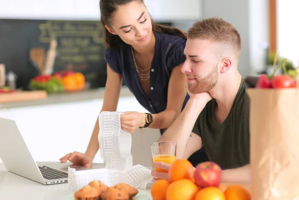 对夫妇支付他们的账单与笔记本电脑在家里的厨房里 — 图库照片