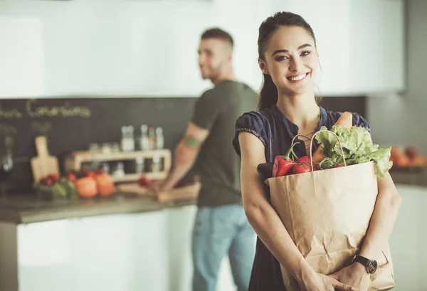 Jong stel in de keuken, vrouw met een zak boodschappen doen — Stockfoto