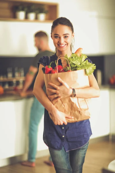 Jeune couple dans la cuisine, femme avec un sac d'épicerie — Photo