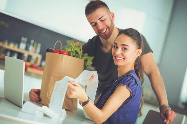 Koppel het betalen van hun rekeningen met laptop in de keuken thuis — Stockfoto