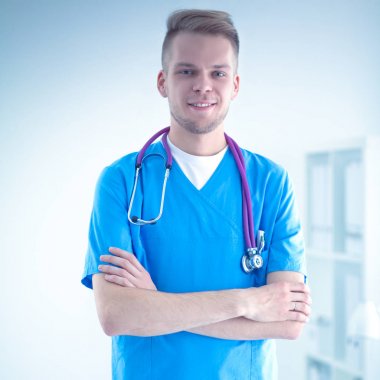 Steteskoplu doktor ayakta, çapraz kollu, beyaz arka planda izole.