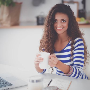 evde mutfakta laptop ile gülümseyen genç kadın