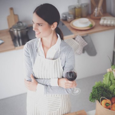 Güzel kadın mutfakta şarap içiyor.