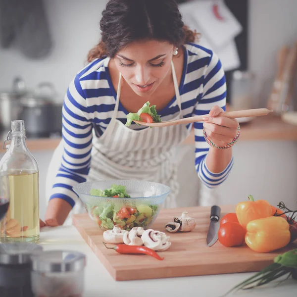 若いです女性食べる新鮮なサラダで現代的なキッチン — ストック写真