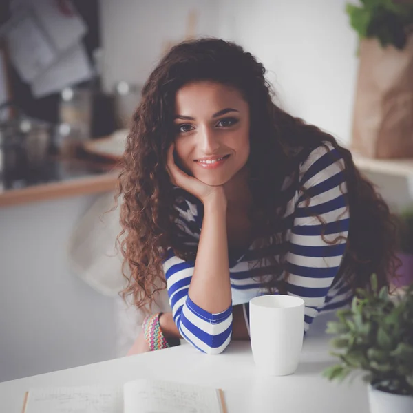 Smiling young woman with laptop in the kitchen at home — Stock Photo, Image
