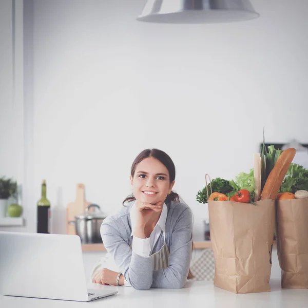 Leende ung kvinna i köket nära skrivbord — Stockfoto